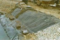 A partszegély kialakítása: műanyag hálóval erősített betonréteg akadályozza meg, hogy a kövek beleguruljanak a tóba.